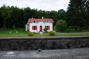 Schleusenhaus 16 am Saar-Kohlekanal. Weiß mit roten Fenstern und Tür, Ziegeldach.
